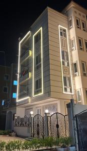 a building with a fence in front of it at night at Modern apartment in Madinat Al Ashir min Ramadan