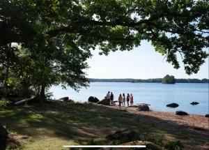 Un groupe de personnes debout sur la rive d'un lac dans l'établissement Beautiful Home in the Swedish landscape, à Vissefjärda