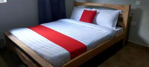 a bed with a red and white blanket and pillows at Tusubira village in Jinja