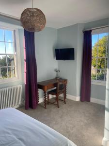 1 dormitorio con escritorio, TV y ventanas en The Castle Inn Bradford on Avon en Bradford on Avon