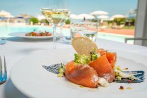 un piatto bianco con sushi su un tavolo con piscina di Hotel Airone isola d'Elba a Portoferraio