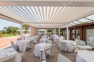 een restaurant met witte tafels en stoelen op een patio bij Hotel Airone isola d'Elba in Portoferraio