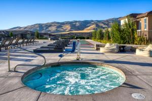 a hot tub on a patio with mountains in the background at Luxury Retreat - King Beds, Hot Tub, & Pool - Family & Remote Work Friendly in Reno