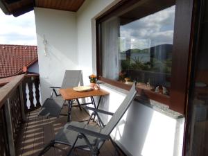 einen Balkon mit Stühlen, einem Tisch und einem Fenster in der Unterkunft Ederauenblick in Dodenau