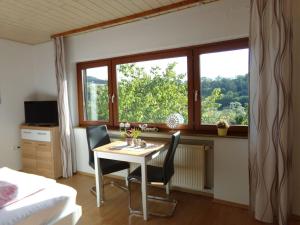 Zimmer mit einem Tisch, Stühlen und einem Fenster in der Unterkunft Ederauenblick in Dodenau