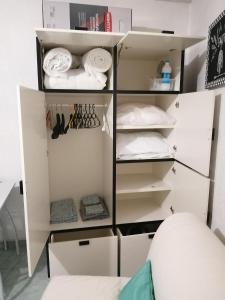un placard avec des étagères blanches et des serviettes blanches dans l'établissement Joli studio bord de mer, clim, balcon, parking privé, à Menton