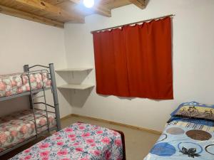 Zimmer mit 2 Etagenbetten und einem roten Vorhang in der Unterkunft La Tranquera Apartamentos in Malargüe