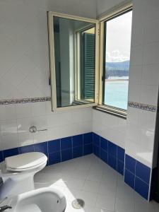 La salle de bains est pourvue de toilettes, d'un lavabo et d'une fenêtre. dans l'établissement Vient Mpop con terrazza vista mare, à Meta