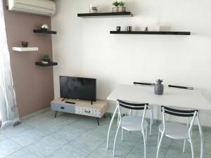 un salon avec une table, des chaises et une télévision dans l'établissement Joli studio bord de mer, clim, balcon, parking privé, à Menton
