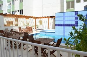 a balcony with tables and chairs and a swimming pool at Apto em Cabo Frio com conforto e qualidade. in Cabo Frio