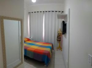 ein Schlafzimmer mit einem farbenfrohen Bett und einem Spiegel in der Unterkunft Apto em Cabo Frio com conforto e qualidade. in Cabo Frio