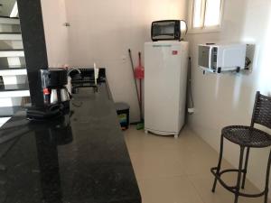 a kitchen with a black counter and a refrigerator at PRAIA GRANDE LOFT DUPLEX in Arraial do Cabo