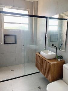 uma casa de banho com uma cabina de duche em vidro e um lavatório. em Cobertura Pé na Areia e Incrível Vista Para a Praia em São Vicente