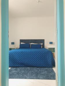 um quarto com uma cama azul com duas almofadas em Cobertura Pé na Areia e Incrível Vista Para a Praia em São Vicente