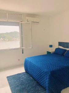 um quarto com uma cama azul e uma janela em Cobertura Pé na Areia e Incrível Vista Para a Praia em São Vicente