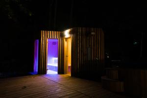 Apartmány NONE في برانا: باب مفتوح مع أضواء أرجوانية في غرفة مظلمة