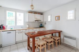 a kitchen with white cabinets and a wooden table at Maison Avocette - Welkeys in Saint-Trojan-les-Bains