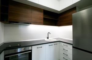 a kitchen with white cabinets and a sink and a refrigerator at Apartment Lara in Belgrade