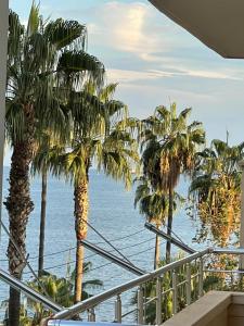 een balkon met palmbomen en uitzicht op de oceaan bij Şehrin kalbindeki deniz manzaralı 3+1 ev in Mersin
