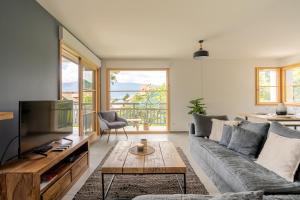 a living room with a couch and a tv at Talloires Village, Lac d'Annecy, Résidence récente 4 étoiles in Talloires