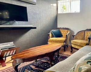 a living room with a table and chairs and a tv at Milnerton Cottage in Cape Town