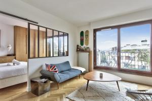 ein Wohnzimmer mit einem Bett, einem Sofa und einem Tisch in der Unterkunft Superb 1 bedroom flat with balcony near the Eiffel Tower - Paris - Welkeys in Paris