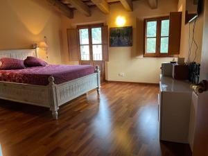 a bedroom with a bed and wooden floors and windows at Riudaura in Riudaura