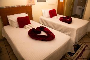 two beds with red pillows on them in a room at The Cottage in Rustenburg