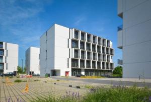 a large white building in front of a parking lot at Apartament AirPort in Wrocław