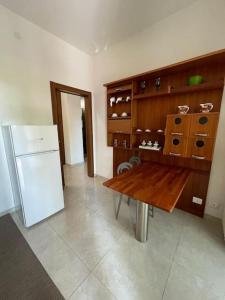 a kitchen with a wooden table and a refrigerator at Terrace house appartamento mq 80 adiacente ospedale e clinica in Piacenza