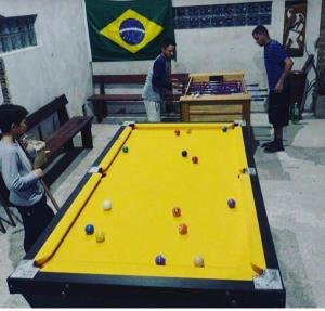 eine Gruppe von Menschen, die um einen Billardtisch stehen in der Unterkunft Pousada das Palmeiras in Pelotas