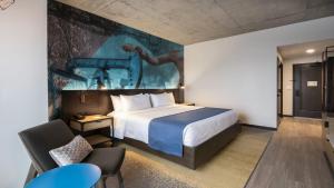 Hotel Indigo Tulsa DWTN/Entertainment Area في تولسا: غرفة فندق فيها سرير و لوحة على الحائط