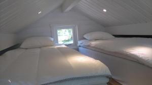 twee bedden in een kleine kamer met een raam bij Strandstugan, Solviken in Rockneby