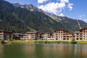 a group of buildings next to a lake with a mountain at Modern 2BR 5* pool gym spa garage Mont-Blanc view in Chamonix-Mont-Blanc