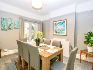 comedor con mesa de madera y sillas en Homely 4 Bedroom large house inc FREE Parking - Great Location - Fast WiFi - Smart TV - sleeps up to 7! Close to Bournemouth & Poole Town Centre & Sandbanks en Bournemouth