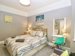 a bedroom with a bed and a green chair at Homely 4 Bedroom large house inc FREE Parking - Great Location - Fast WiFi - Smart TV - sleeps up to 7! Close to Bournemouth & Poole Town Centre & Sandbanks in Bournemouth