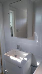 a white bathroom with a sink and a mirror at Strandstugan, Solviken in Rockneby