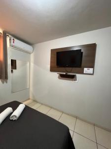 a room with a bed and a flat screen tv at Hotel Castro in Itumbiara