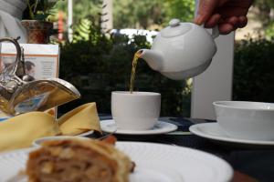 una persona vertiendo café en una taza sobre una mesa en Pousada Don Ramon & Spa Holgar D'Alma - Charm Collection, en Canela