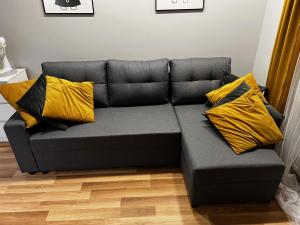 un sofá gris con almohadas amarillas en la sala de estar. en Family & Business Elegant Apartments Rynek Centrum Downtown - 2 Bedroom, Balcony, Parking, en Kielce
