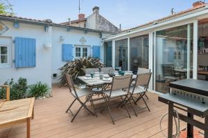 um pátio com uma mesa e cadeiras num deque em Maison des Illustres - Welkeys em La Rochelle