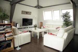 a living room with white couches and a tv at Chambre D'hôtes Les Epicuriens in Épernay