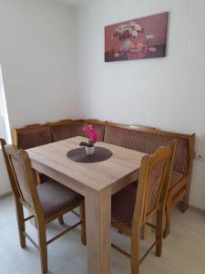 a wooden table with chairs and a vase with flowers on it at Apartment Ildiko in Subotica