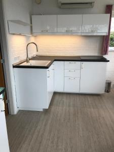 uma cozinha com armários brancos e um lavatório em Hel(t) udlejningsbolig med Christina som vært em Grasten