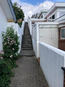 una escalera que conduce a una casa con una valla blanca en Hel(t) udlejningsbolig med Christina som vært, en Gråsten