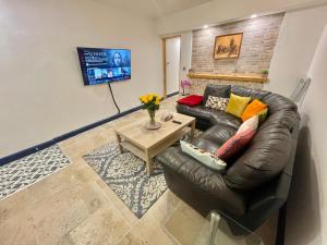 a living room with a leather couch and a table at Cathedral view Cottage in Gloucester