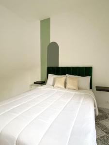 a bedroom with a large white bed with a green headboard at Cosy appartement Next to Majorelle Garden in Marrakech