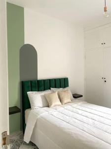 a bedroom with a large bed with a green headboard at Cosy appartement Next to Majorelle Garden in Marrakech