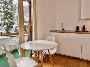 una cocina con una mesa y sillas blancas y una ventana en Apartmenthaus am Tegernsee - Studios mit Küchenzeile und mit Bus erreichbar, en Bad Wiessee