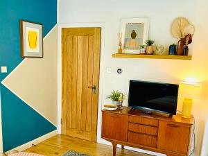 a living room with a television on a wooden dresser at St Ives Balcony Flat in St Ives